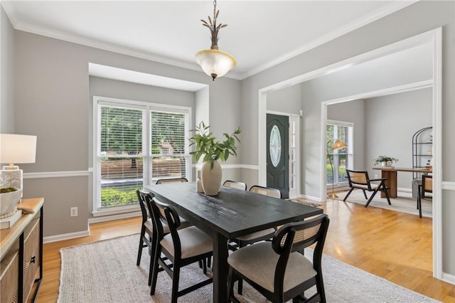 dining area featuring baseboards, ornamental molding, and light wood finished floors