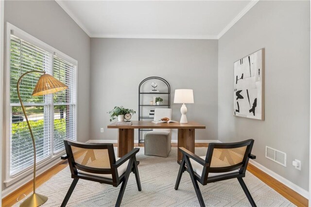 office space with light wood-type flooring, visible vents, baseboards, and ornamental molding