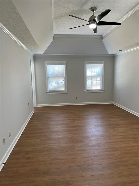 unfurnished room with ornamental molding, vaulted ceiling, dark hardwood / wood-style flooring, a textured ceiling, and ceiling fan