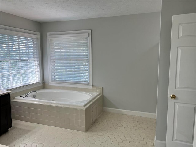 bathroom with vanity, tiled bath, a textured ceiling, and tile patterned flooring