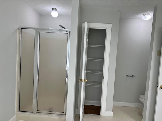 bathroom featuring toilet, a textured ceiling, and an enclosed shower