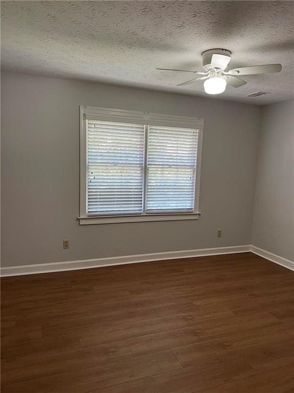 spare room with a textured ceiling, dark wood-type flooring, and ceiling fan