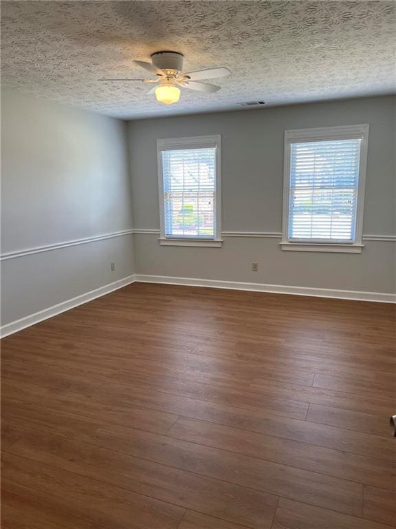 empty room with a textured ceiling, dark hardwood / wood-style floors, and ceiling fan