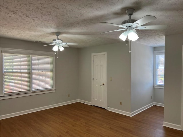 empty room with ceiling fan, a wealth of natural light, and dark hardwood / wood-style flooring