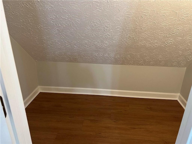 additional living space featuring dark wood-type flooring and vaulted ceiling