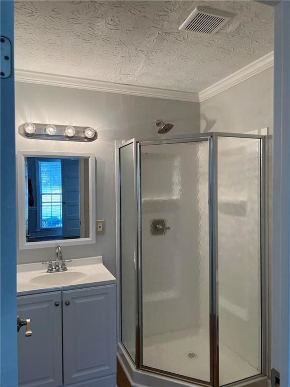 bathroom with vanity, crown molding, a textured ceiling, and a shower with door