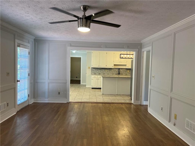 kitchen featuring backsplash, ceiling fan, white cabinets, crown molding, and light hardwood / wood-style flooring