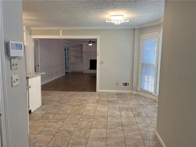 interior space featuring light tile patterned floors, ornamental molding, and a textured ceiling