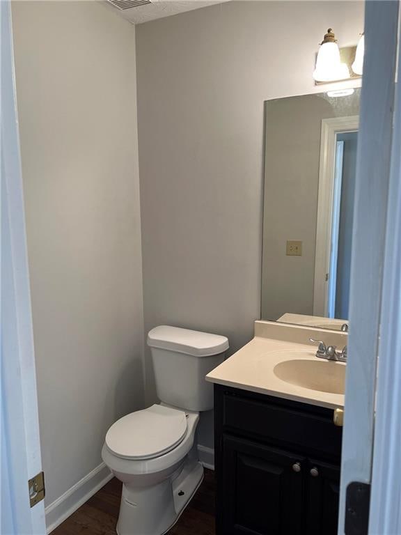 bathroom with vanity, toilet, and wood-type flooring