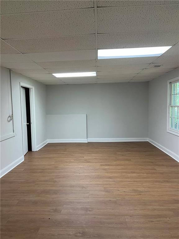 empty room featuring wood-type flooring and a paneled ceiling