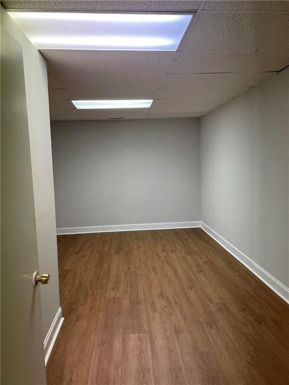 empty room featuring a drop ceiling and hardwood / wood-style flooring