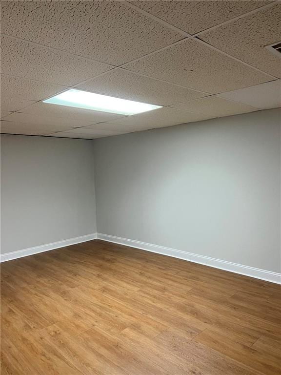 unfurnished room with a drop ceiling and hardwood / wood-style flooring