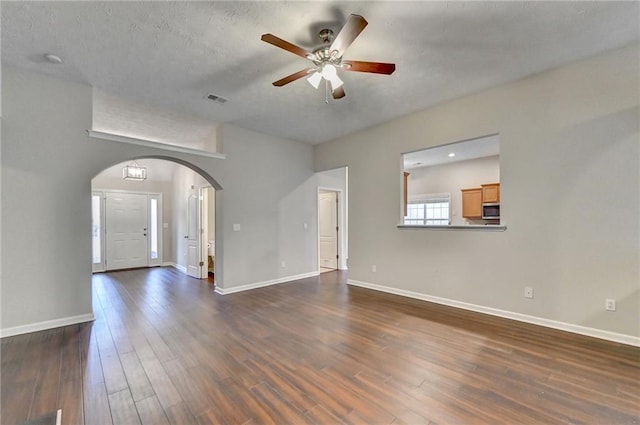 unfurnished living room with arched walkways, visible vents, dark wood finished floors, and baseboards