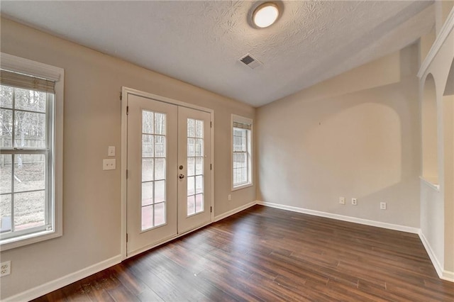 doorway to outside featuring a wealth of natural light, french doors, dark wood finished floors, and a textured ceiling