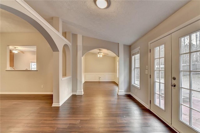 entrance foyer featuring a wealth of natural light, arched walkways, french doors, and dark wood finished floors