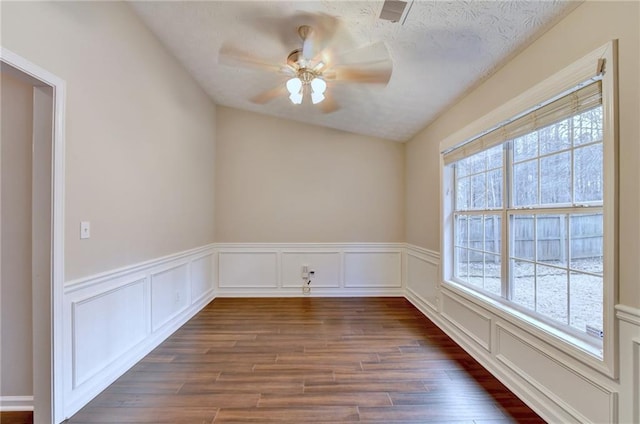 unfurnished room with dark wood-style flooring, ceiling fan, and a decorative wall