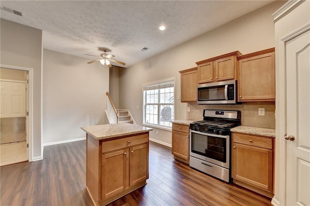 kitchen with tasteful backsplash, visible vents, a kitchen island, appliances with stainless steel finishes, and dark wood-type flooring