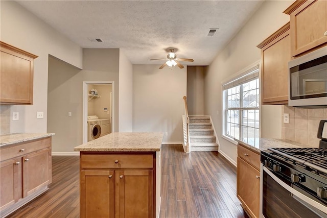 kitchen with light stone countertops, gas range, visible vents, and stainless steel microwave