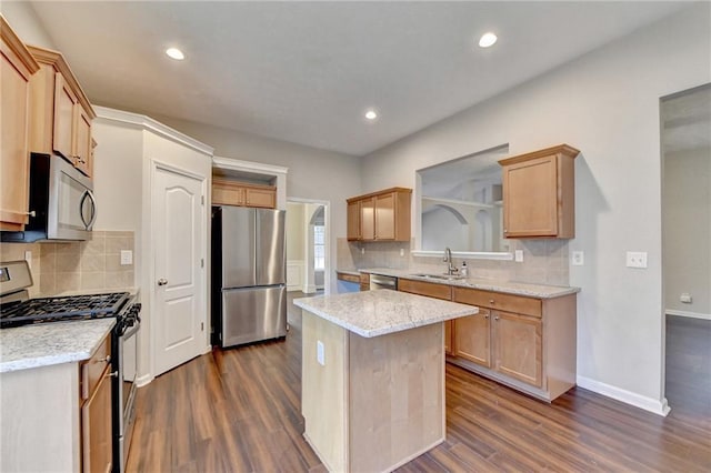 kitchen with appliances with stainless steel finishes, dark wood-type flooring, a kitchen island, a sink, and light stone countertops