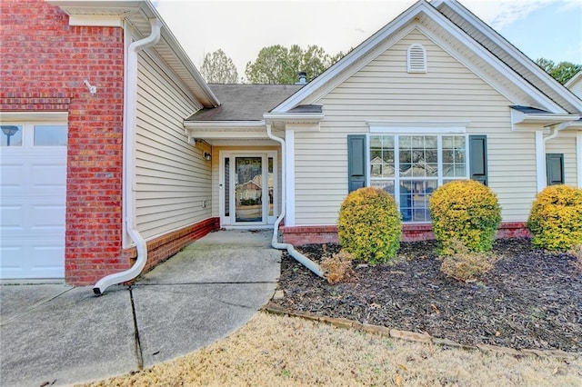 property entrance featuring a garage and brick siding