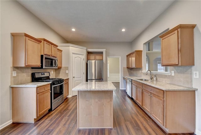 kitchen featuring light stone counters, light brown cabinets, stainless steel appliances, a sink, and a center island