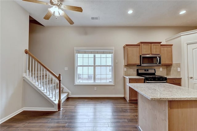 kitchen with baseboards, dark wood finished floors, visible vents, decorative backsplash, and stainless steel appliances