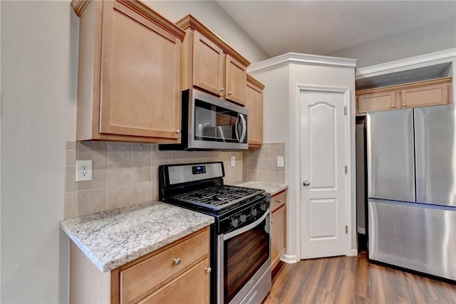 kitchen featuring stainless steel appliances, decorative backsplash, light brown cabinetry, dark wood-type flooring, and light stone countertops