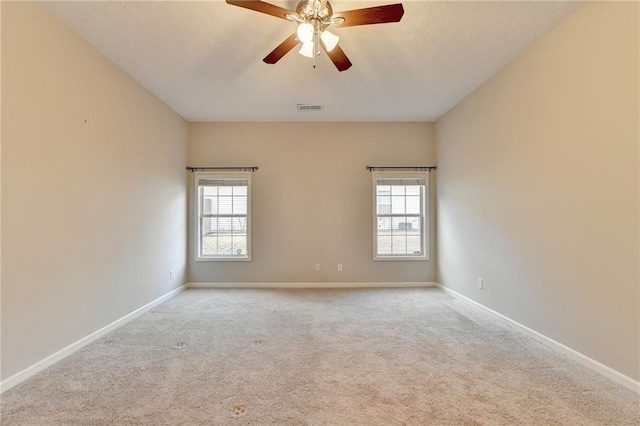 empty room featuring light colored carpet, visible vents, and baseboards