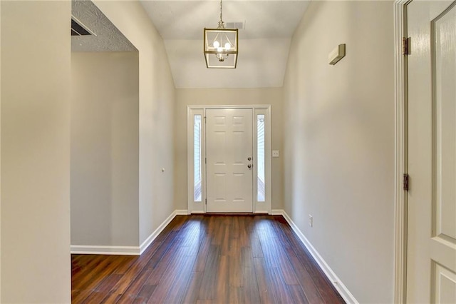 entryway featuring vaulted ceiling, baseboards, dark wood finished floors, and a chandelier