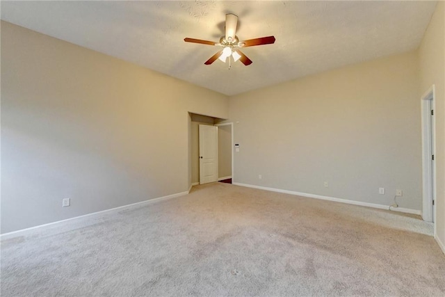 empty room featuring light carpet, a ceiling fan, and baseboards