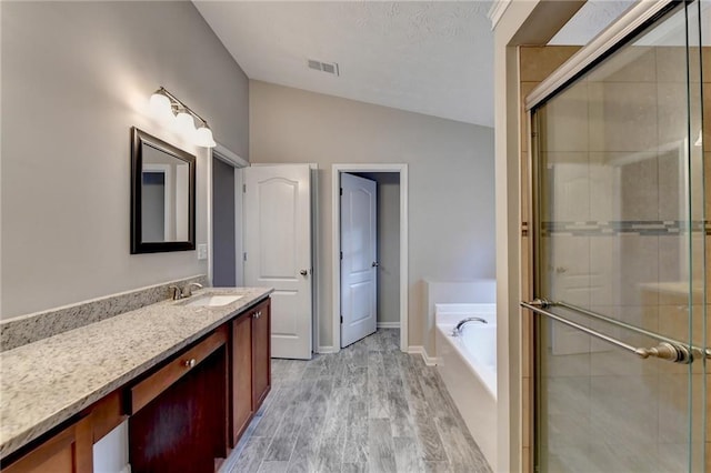 bathroom featuring a garden tub, vanity, visible vents, vaulted ceiling, and a stall shower