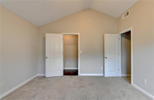 unfurnished bedroom featuring lofted ceiling, visible vents, light carpet, and baseboards