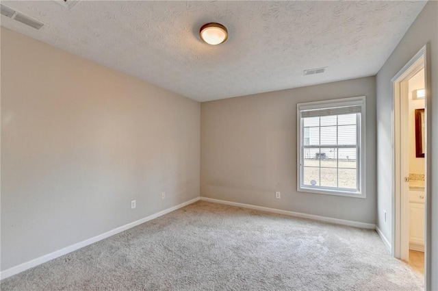 unfurnished bedroom with visible vents, light carpet, baseboards, and a textured ceiling