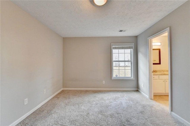 unfurnished bedroom with visible vents, light carpet, baseboards, and a textured ceiling