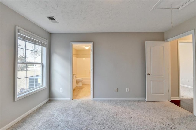 unfurnished bedroom with baseboards, a textured ceiling, visible vents, and attic access