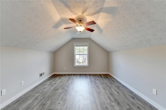 bonus room featuring light wood-type flooring, baseboards, visible vents, and a textured ceiling