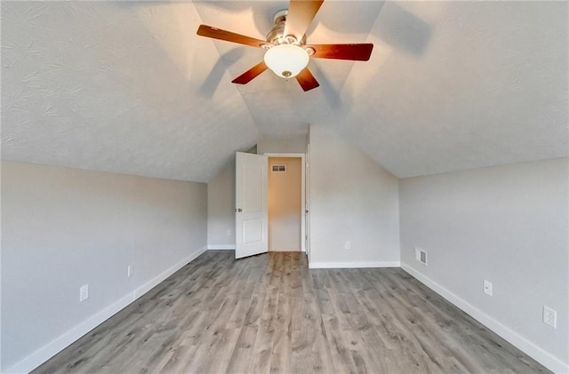 additional living space featuring vaulted ceiling, light wood-style flooring, baseboards, and ceiling fan