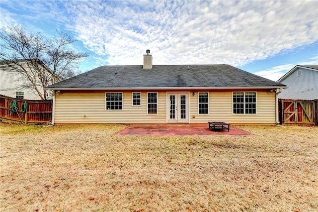 back of house featuring french doors, a patio, a fenced backyard, a chimney, and a yard