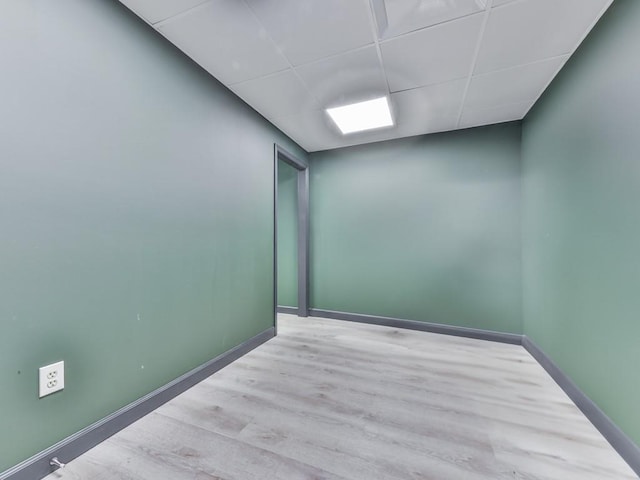 interior space featuring baseboards, wood finished floors, and a paneled ceiling