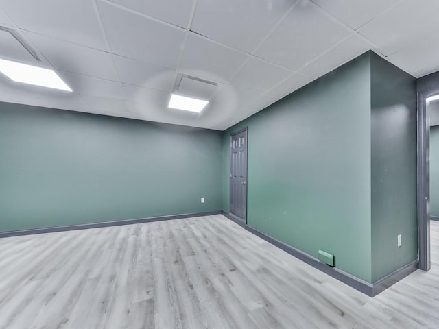 unfurnished room featuring baseboards, a paneled ceiling, and wood finished floors