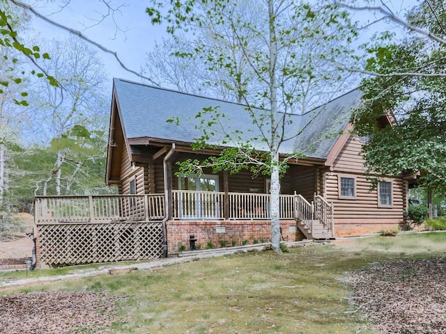 log-style house with log exterior, a shingled roof, and covered porch