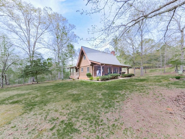 view of side of home with a yard, log exterior, and a chimney
