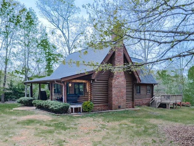 view of home's exterior with a chimney, log siding, a yard, and a deck