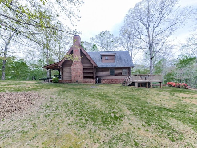 rear view of house with a chimney, log siding, a yard, and a deck