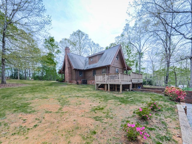 back of property featuring central AC, a chimney, log exterior, a deck, and a yard