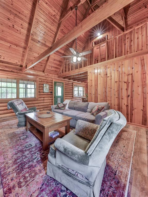living area featuring wood ceiling, wood finished floors, a wealth of natural light, and beamed ceiling