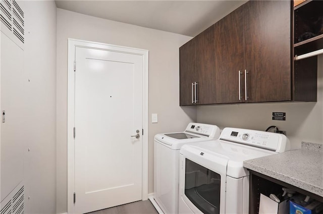 laundry room featuring separate washer and dryer and cabinets