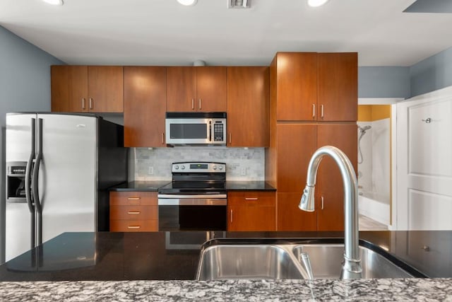 943 Peachtree St NE Unit 1109, Atlanta, GA 30309 - kitchen featuring tasteful backsplash, dark stone countertops, sink, and stainless steel appliances