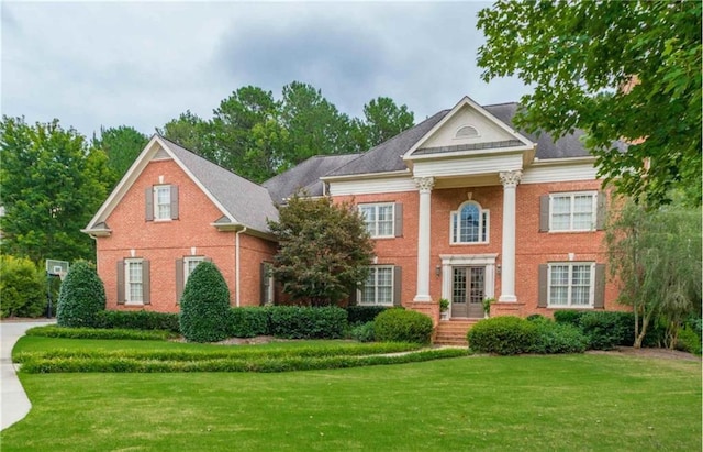 greek revival inspired property featuring a front lawn and brick siding