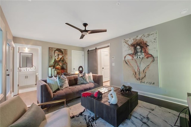 living room featuring ceiling fan, light hardwood / wood-style flooring, and a barn door